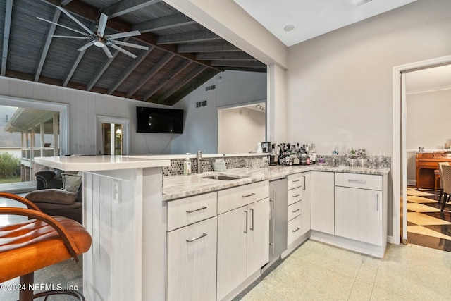 kitchen with kitchen peninsula, a kitchen bar, ceiling fan, sink, and lofted ceiling with beams