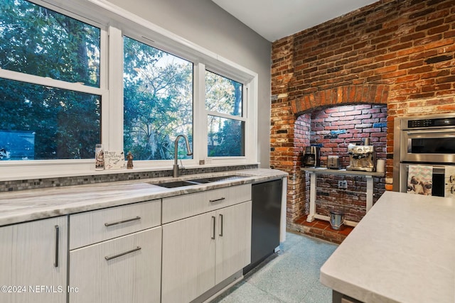 kitchen with dishwasher, brick wall, sink, and double oven