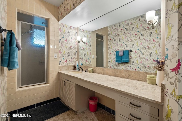 bathroom featuring tile patterned flooring, vanity, a shower with shower door, and tile walls