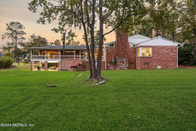 back house at dusk featuring a yard