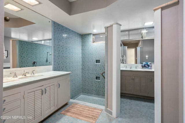 bathroom with tile patterned flooring, vanity, and a tile shower