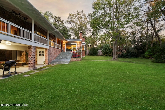 yard at dusk with ceiling fan and a patio