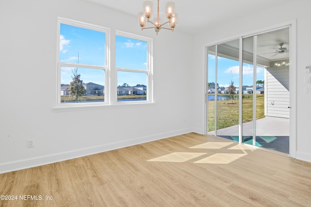 unfurnished room featuring ceiling fan with notable chandelier and light hardwood / wood-style floors