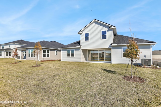 rear view of house featuring a lawn and central AC