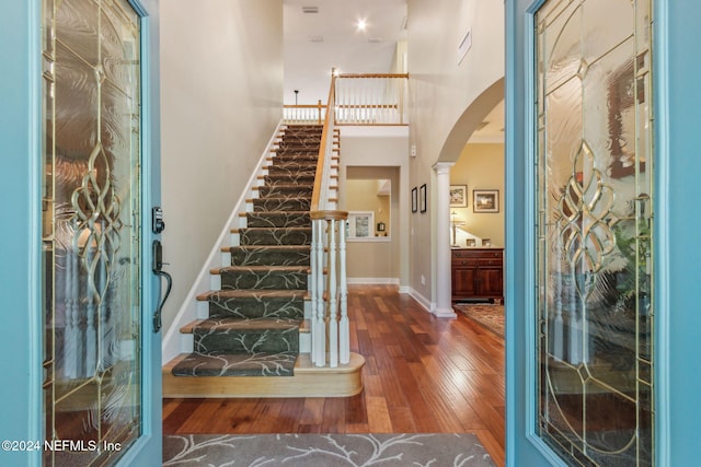 foyer entrance with decorative columns and dark wood-type flooring