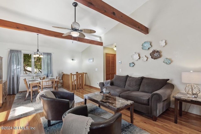 living room with lofted ceiling with beams, ceiling fan with notable chandelier, and light wood-type flooring