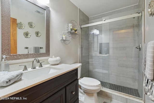 bathroom with tile patterned flooring, vanity, an enclosed shower, and toilet