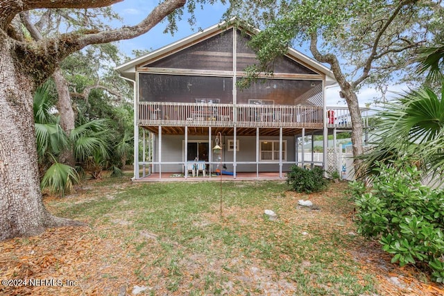 back of property with a lawn, a patio area, and a sunroom