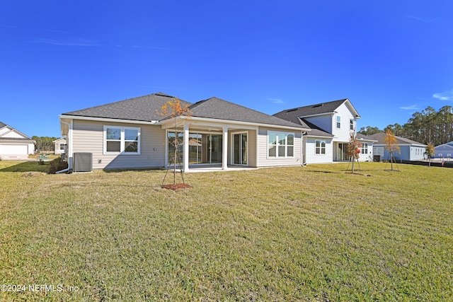 rear view of property featuring central AC unit and a lawn