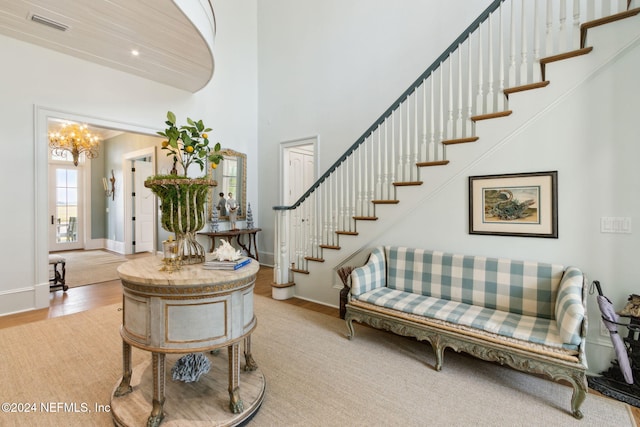 foyer with a towering ceiling, light hardwood / wood-style floors, and an inviting chandelier