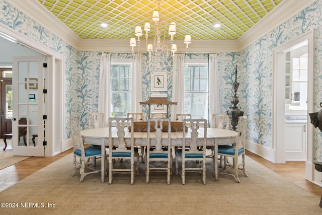 dining space with a chandelier, french doors, crown molding, and light hardwood / wood-style flooring