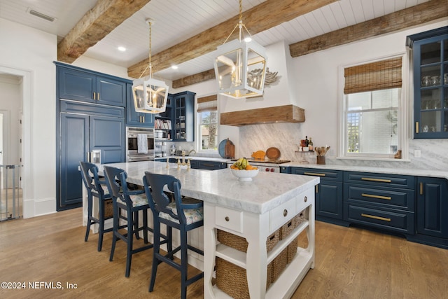 kitchen featuring blue cabinetry, decorative backsplash, plenty of natural light, and a kitchen island with sink