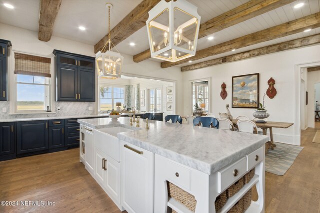 kitchen featuring plenty of natural light, an island with sink, pendant lighting, and light wood-type flooring