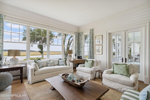 sunroom / solarium with french doors, a water view, and a healthy amount of sunlight