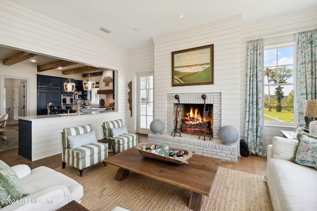 living room with a fireplace, wood-type flooring, and beamed ceiling