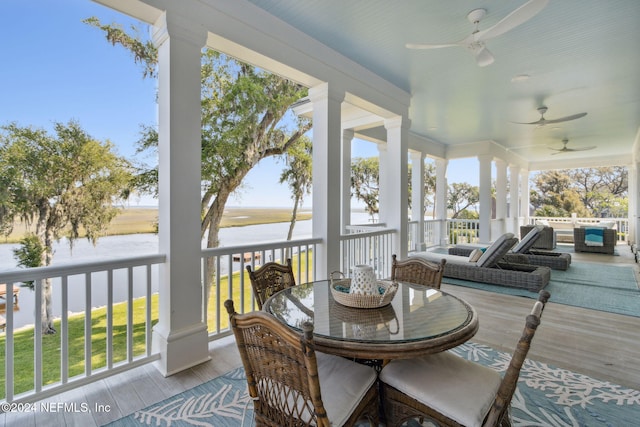 sunroom / solarium with ceiling fan and a water view