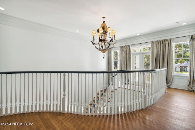 corridor featuring hardwood / wood-style floors, ornamental molding, and an inviting chandelier