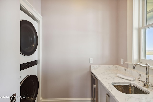 clothes washing area featuring stacked washing maching and dryer and sink