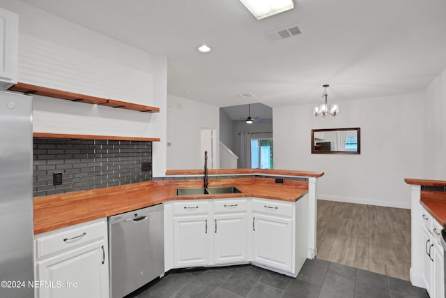 kitchen with wood counters, sink, hanging light fixtures, appliances with stainless steel finishes, and white cabinets