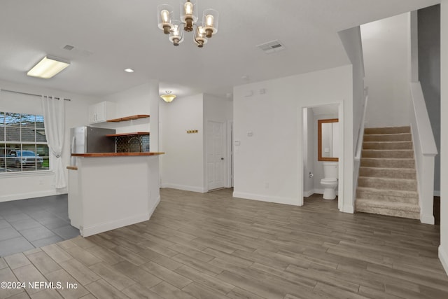 unfurnished living room with wood-type flooring and a notable chandelier