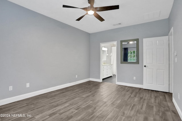 unfurnished bedroom with ceiling fan, ensuite bathroom, and hardwood / wood-style floors