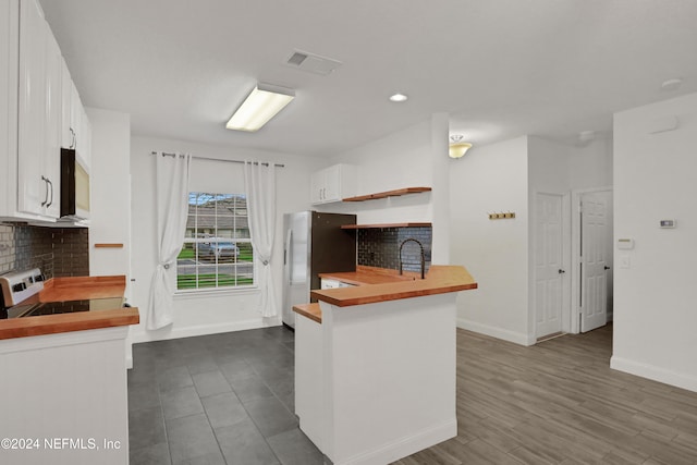 kitchen featuring appliances with stainless steel finishes, wood counters, tasteful backsplash, white cabinets, and kitchen peninsula