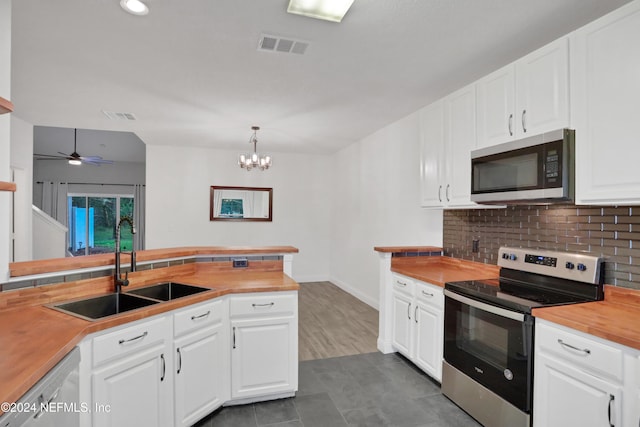 kitchen featuring appliances with stainless steel finishes, decorative light fixtures, butcher block countertops, and white cabinets