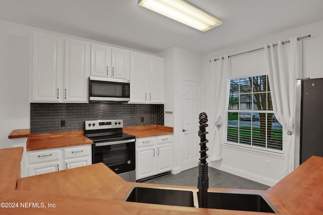 kitchen featuring tasteful backsplash, appliances with stainless steel finishes, white cabinets, and butcher block countertops