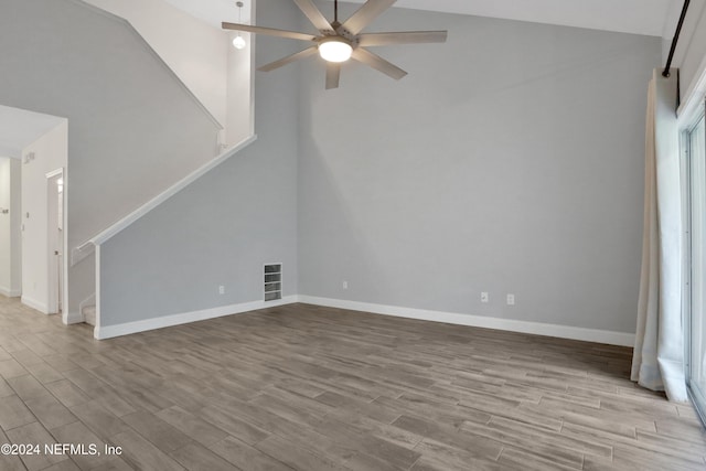 unfurnished living room featuring ceiling fan, a towering ceiling, and light hardwood / wood-style floors