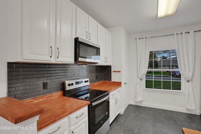 kitchen featuring appliances with stainless steel finishes, wood counters, white cabinets, decorative backsplash, and a textured ceiling