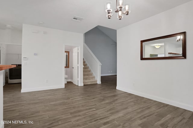 unfurnished living room featuring a notable chandelier and dark wood-type flooring