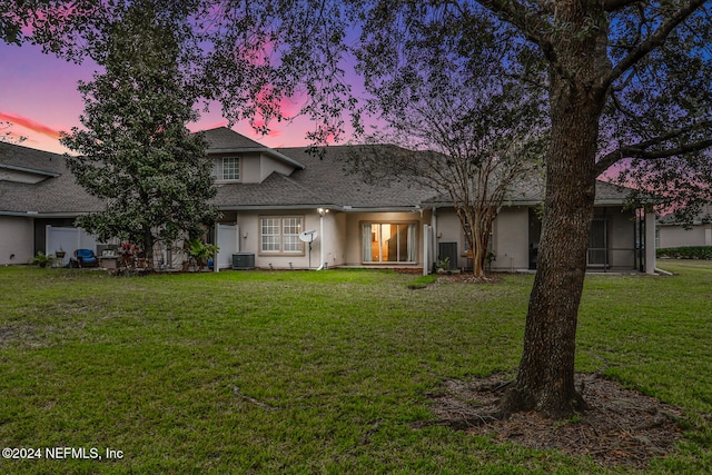 back house at dusk featuring a lawn