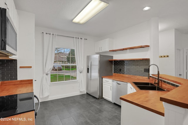 kitchen with sink, white cabinetry, backsplash, stainless steel appliances, and wood counters