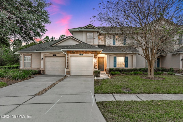 front of property with a garage and a lawn