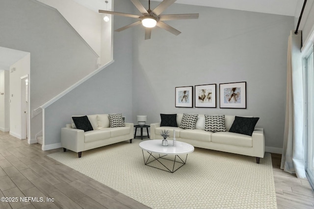 living room with ceiling fan, light hardwood / wood-style floors, and a high ceiling