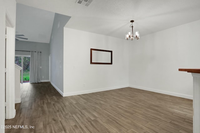 unfurnished room with wood-type flooring, lofted ceiling, and an inviting chandelier