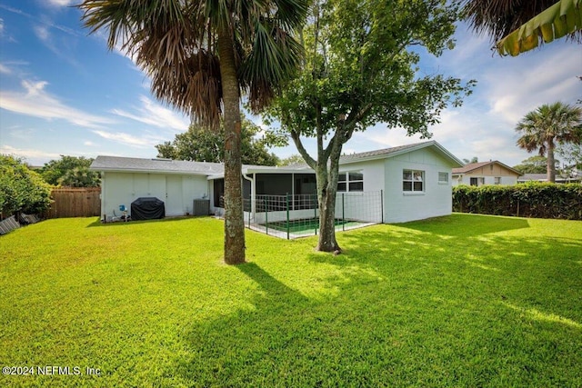 rear view of house featuring central AC unit, a lawn, and a sunroom