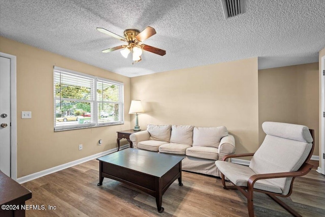 living room with ceiling fan, a textured ceiling, and hardwood / wood-style flooring