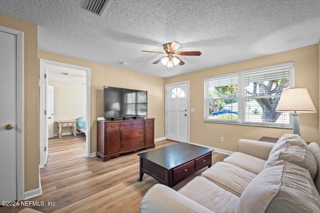 living room featuring ceiling fan, light hardwood / wood-style floors, and a textured ceiling