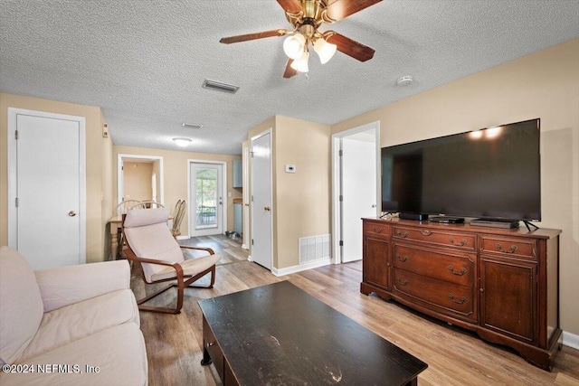 living room with a textured ceiling, light wood-type flooring, and ceiling fan