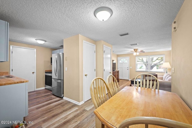 dining room featuring hardwood / wood-style flooring, ceiling fan, sink, and a textured ceiling