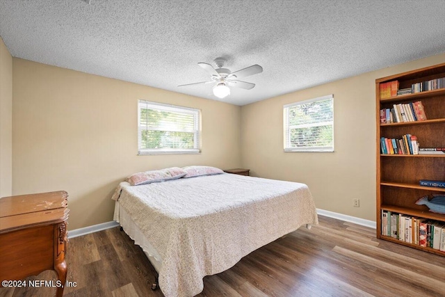 bedroom with a textured ceiling, dark hardwood / wood-style floors, multiple windows, and ceiling fan