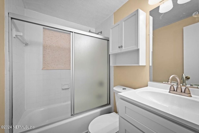 full bathroom with shower / bath combination with glass door, vanity, a textured ceiling, and toilet