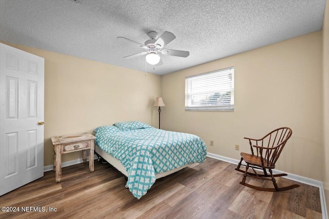 bedroom featuring ceiling fan, hardwood / wood-style floors, and a textured ceiling