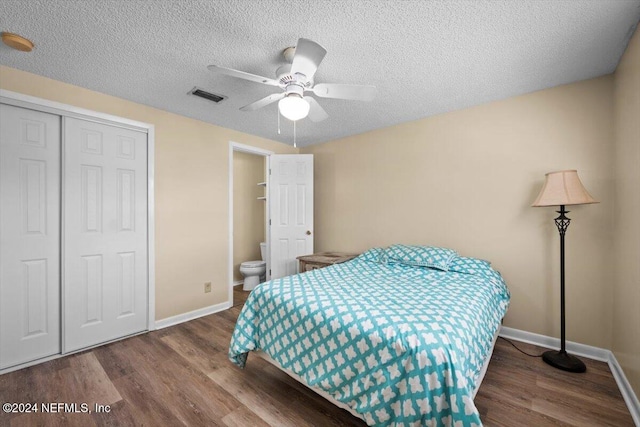 bedroom with ensuite bath, a textured ceiling, ceiling fan, hardwood / wood-style flooring, and a closet