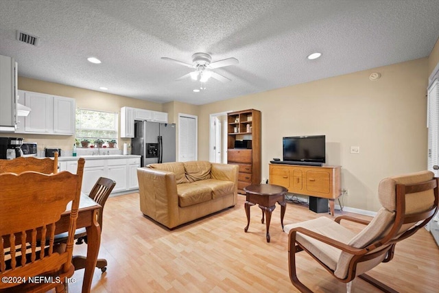 living room with ceiling fan, sink, a textured ceiling, and light hardwood / wood-style flooring