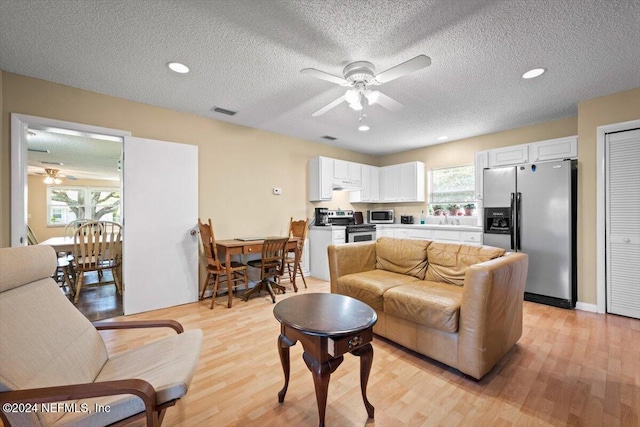 living room with a healthy amount of sunlight, sink, a textured ceiling, and light hardwood / wood-style flooring