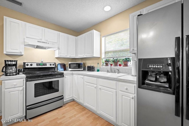 kitchen featuring sink, stainless steel appliances, light hardwood / wood-style flooring, a textured ceiling, and white cabinets