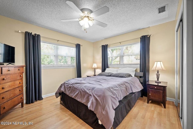 bedroom featuring ceiling fan, light hardwood / wood-style floors, a textured ceiling, and a closet