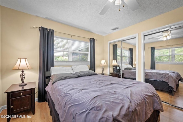 bedroom with a textured ceiling, light hardwood / wood-style flooring, multiple windows, and ceiling fan